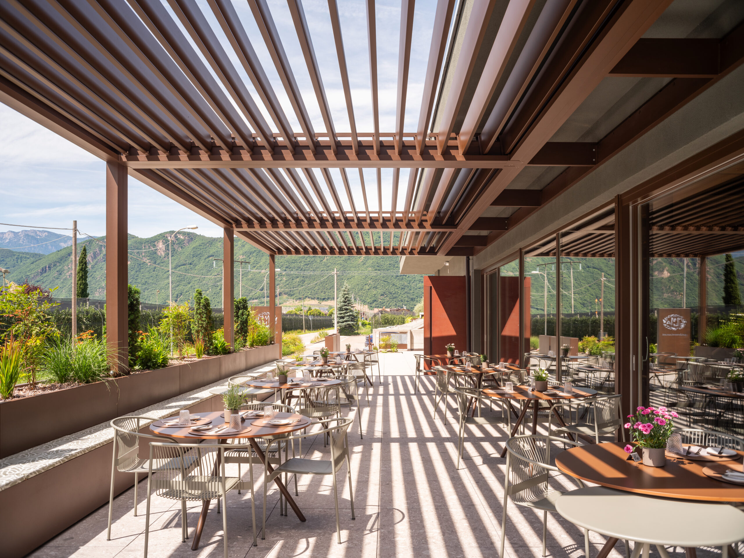 Brustor B200 Lamellendach über Restaurant-Terrasse mit Bergpanorama und Schattenspiel
